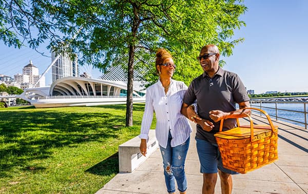 Two people walk along the Milwaukee lakefront passing the beautiful Milwaukee Art Museum.