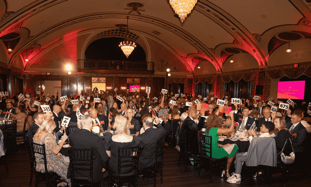 Attendees raise donation paddles at Illuminate: A Night for Cures on Thursday, September 18, 2025
