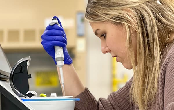 Researcher using a pipette to add a sample.