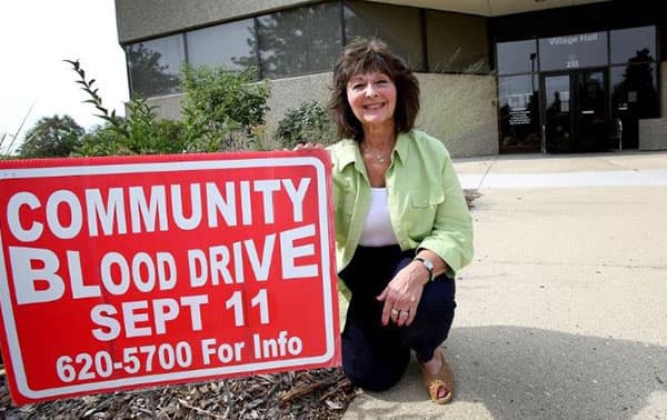 Carol holding a community blood drive sign.