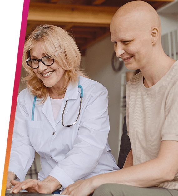 A researcher and smiling cancer patient looking at a laptop screen.