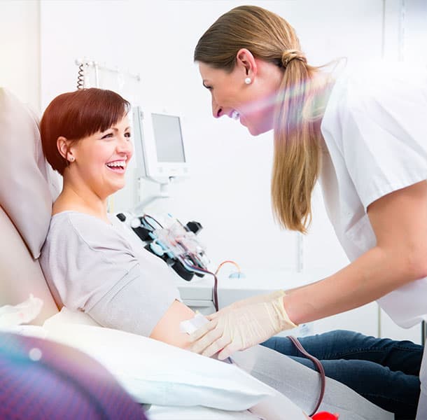 Smiling woman laughing with her phlebotomist during a blood donation.