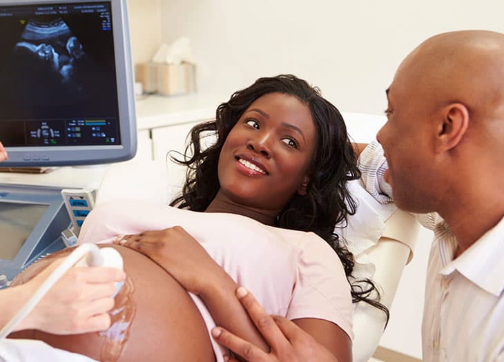 Smiling couple looking at a monitor during an ultrasound examination.
