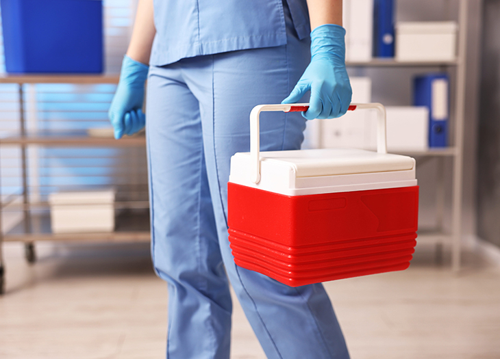 A nurse holding a cooler to transport organs or organ components.