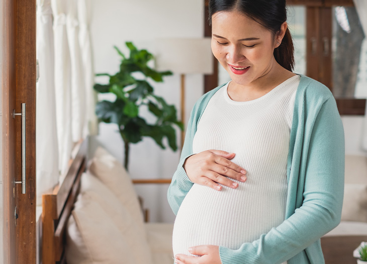 Smiling pregnant woman holding her belly.