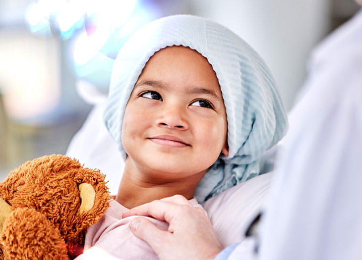Smiling child holding a bear.
