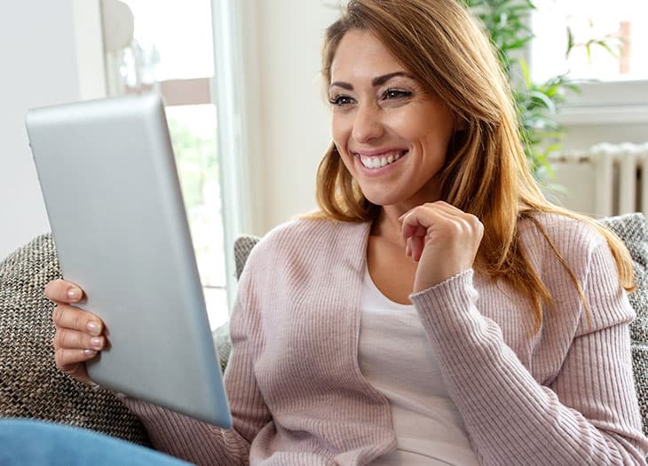 Smiling woman holding a tablet.